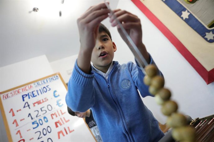 Un niño de la Residencia Internado San Ildefonso coloca números de la Lotería en un alambre, preparándose para la celebración del Sorteo de la Lotería de Navidad del próximo 22 de diciembre, en Madrid a 25 de noviembre de 2019.