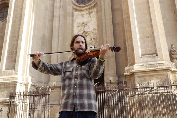 Imagen de un músico tocando frente a la Catedral de Granada