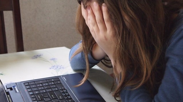 Chica delante de un ordenador angustiada