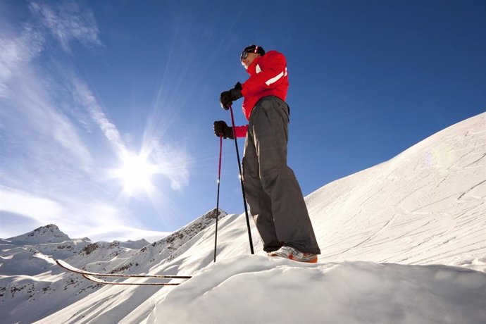 Hombre joven en la montaña, skiando, con el sol de fondo. Nieve. 