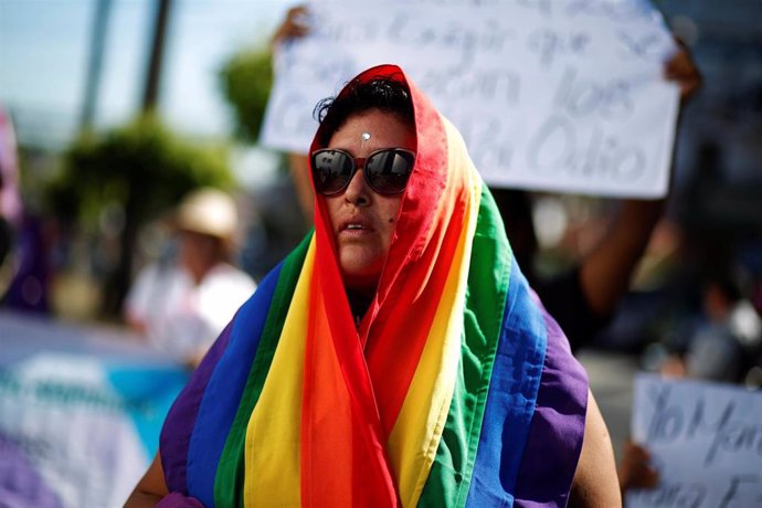 Una mujer cubierta por la bandera LGTB durante las últimas protestas contra la violencia género celebradas en El Salvador.