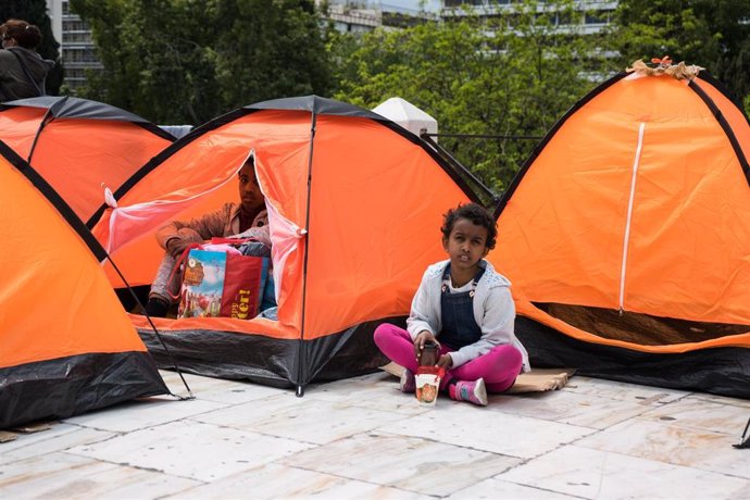 Niños sentados en un campamento esperando ser trasladados en Grecia. 