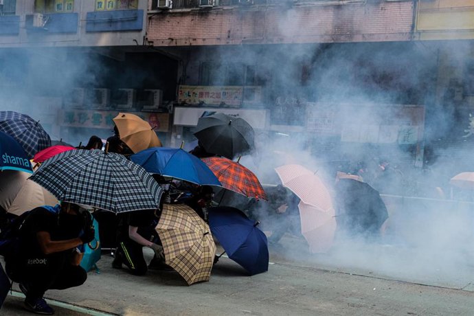 Manifestantes utilizan paraguas para protegerse del lanzamiento de gases lacrimógenos en Hong Kong. 