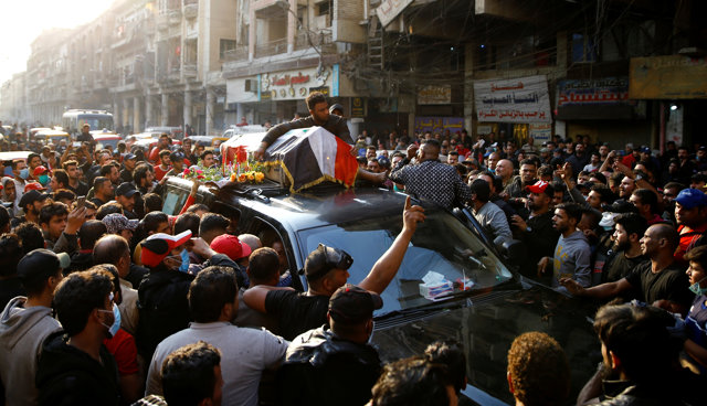A man holds a coffin of his relative who was killed at an anti-government protest, during the funeral in Baghdad, Iraq