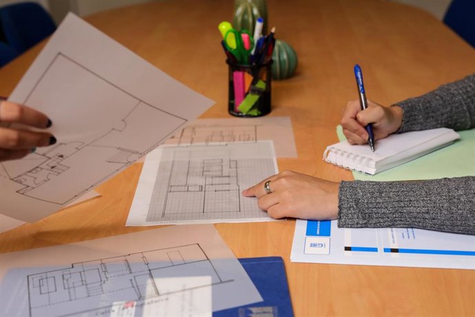 Dos chicas toman notas sobre el plano de una vivienda.