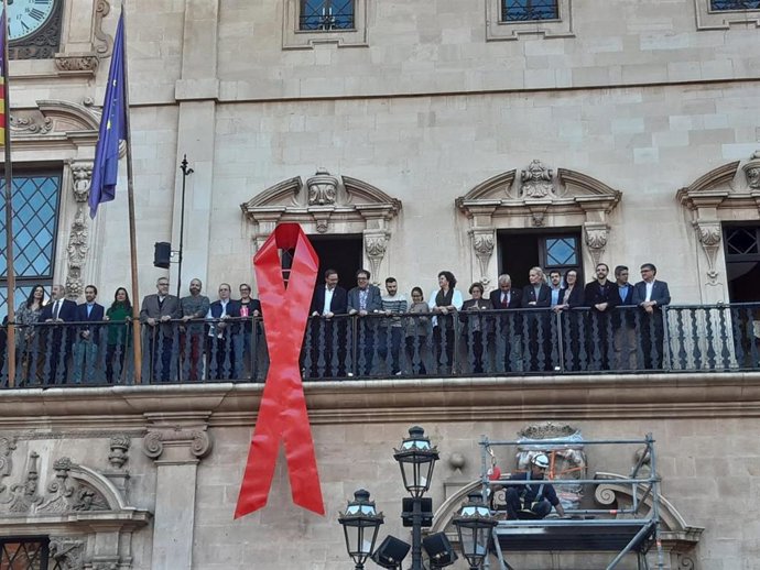 Cuelgan un razo lojo en la fachada de Cort por la lucha contra la estigmatización del SIDA.