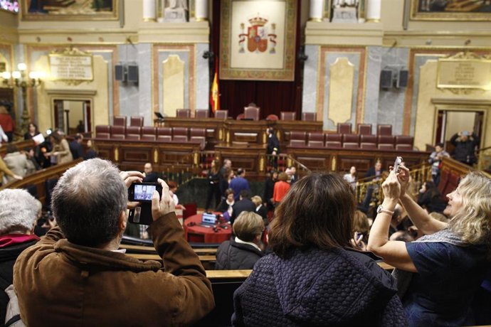 Algunos de los visitantes al Congreso de los Diputados durante la jornada de puertas abiertas, toman fotos del hemiciclo del Congreso.