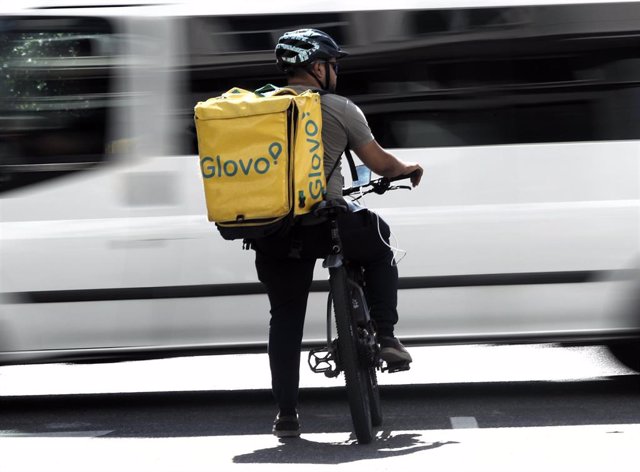 Un rider de la empresa de reparto de comida a domicilio Glovo, pasea por una calle de Madrid con su bicicleta.