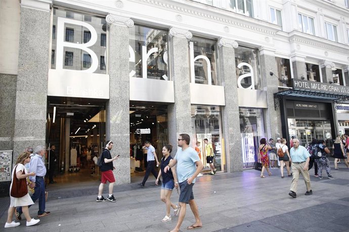 Varias personas pasean por una calle comercial.