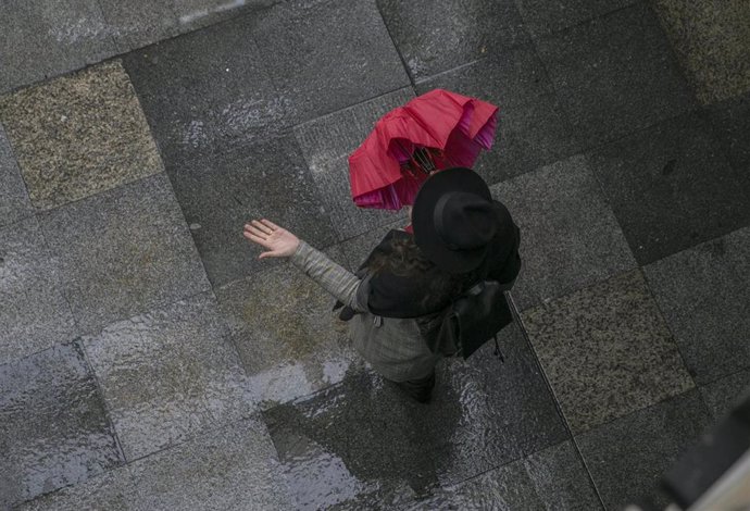Una mujer comprueba si llueve al salir de una galería comercial.