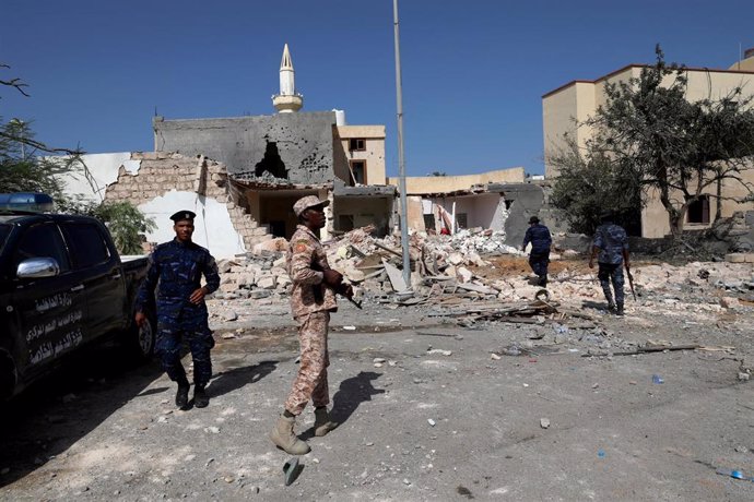 Miembros de seguridad inspeccionan el lugar de un ataque aéreo que golpeó un distrito residencial en Trípoli, Libia