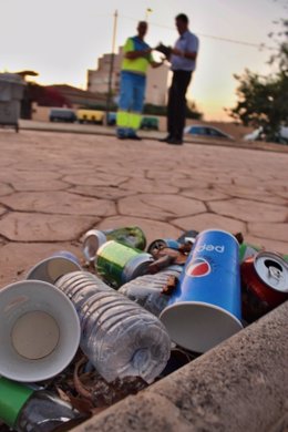 Residuos de vasos desechables y envases de plástico en una calle de Palma, y un operario de Emaya al fondo. 