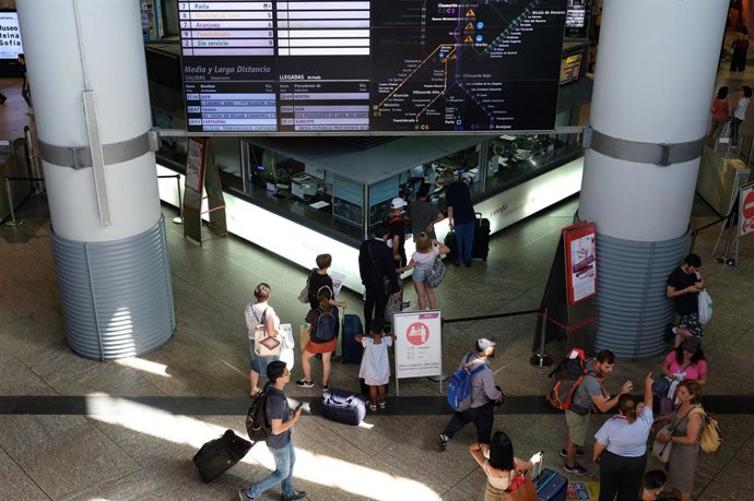 Varios viajeros hacen cola frente a un mostrador con el cartel de 'Renfe Cercanías Madrid' de la estación de trenes de Atocha  