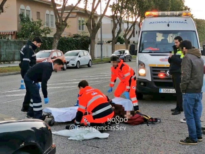 Efectivos sanitarios auxiliar a un joven herido tras ser atropellado en Sevilla capital.