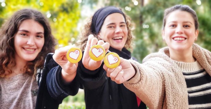 Ana Caballero (Centro) Con Dos Voluntarias De Jesús Abandonado, Sosteniendo Una Chapa Con La Nueva Imagen Del Voluntariado De La Institución