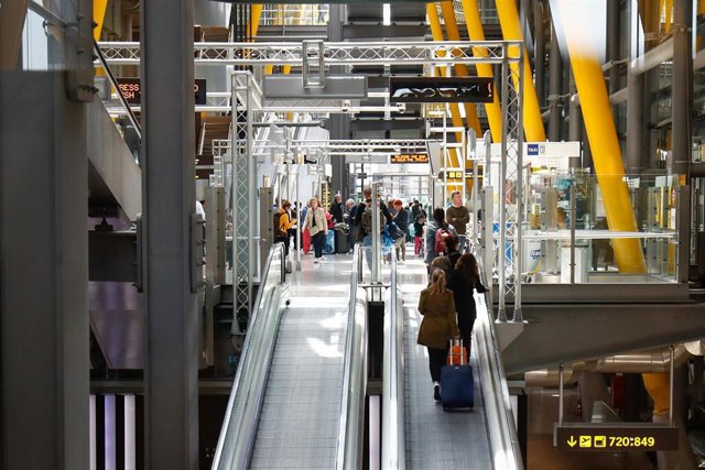Varios viajeros suben por la cinta trasportadora en el T4 del aeropuerto Adolfo Suárez Madrid-Barajas. 