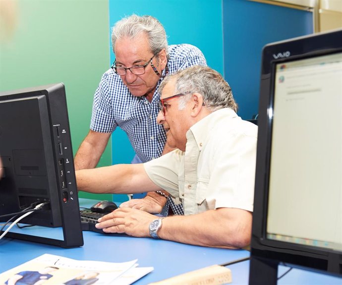 Imagen de dos hombres en una de las actividades para personas mayores sobre informática.
