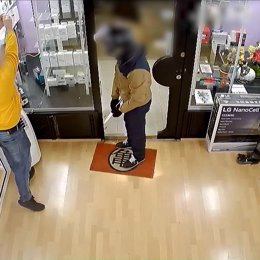 Uno de los presuntos atracadores durante el robo en una tienda de móviles de Barcelona.