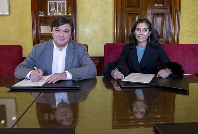 El alcalde de Huelva, Gabriel Cruz, y la directora de Cáritas Diocesana de Huelva, Pilar Vizcaíno, firman un convenio de colaboración.