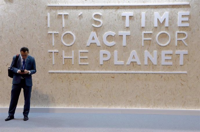 09 December 2019, Spain, Madrid: A man stands in front of a wall with the inscription "It's time to act for the planet",  during the UN Climate Change Conference (COP25). Photo: Clara Margais/dpa