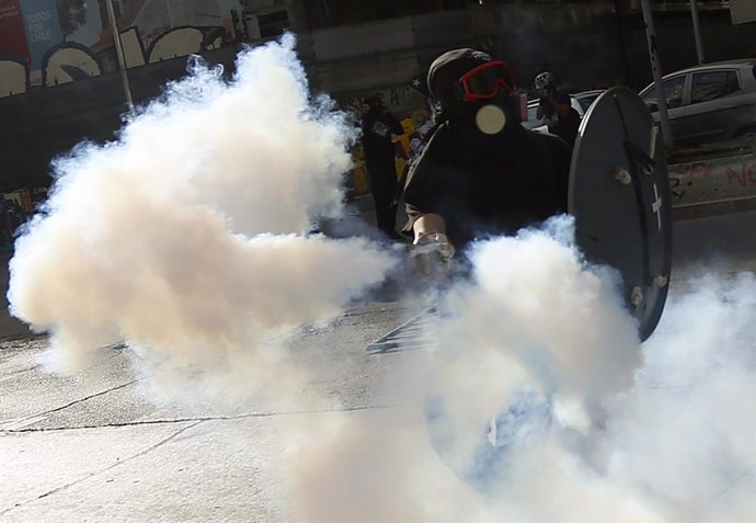 Un manifestant retorna un pot de gasos lacrimgens durant una protesta a Santiago durant el Dia dels Drets Humans.