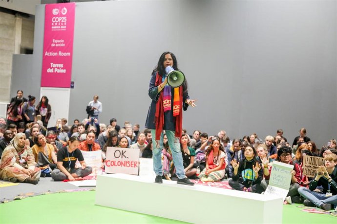 Una activista del movimiento Fridays for Future habla a través de un megáfono durante una sentada en el pabellón 4 en protesta por los resultados "insuficientes" logrados en la Cumbre del Clima (COP25) que se celebra hasta hoy en Ifema, Madrid (España),