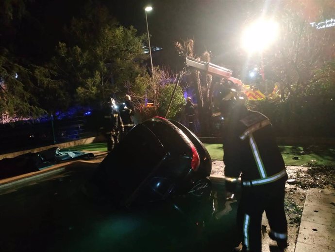 Imagen de los bomberos de la Comunidad de Madrid sacando el coche que ha quedado sumergido en una piscina de una guardería en la localidad de Las Rozas.