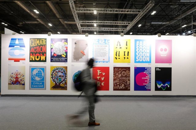 Una persona pasa por delante de unos carteles sobre el cambio climático, en la Cumbre del Clima (COP25) en Ifema, Madrid.