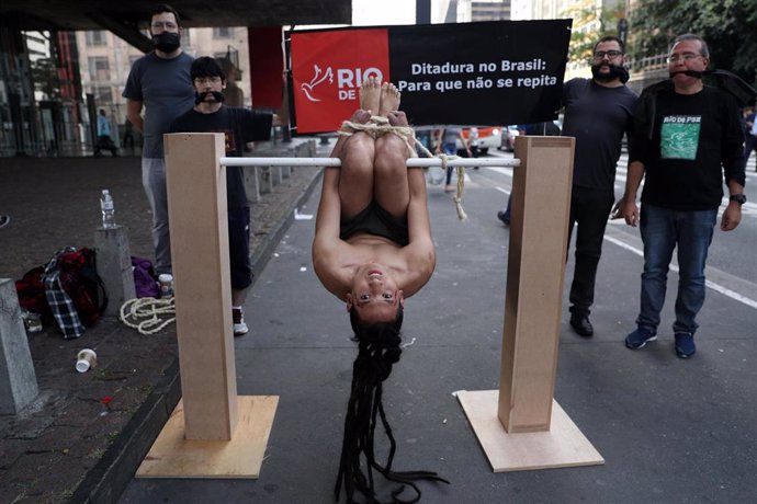Un miembro de la ONG brasileña Río de Paz simulando el método de tortura conocido como 'pau de arara' durante las protestas del 55 aniversario de la dictadura militar en Brasil.
