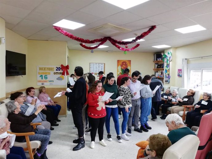 Un grupo de jóvenes sevillanos visita a los mayores de un centro de día y canta villancicos por Navidad