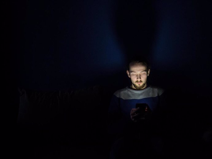 Hombre usando un teléfono móvil de noche.