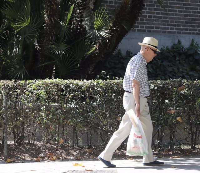 Un hombre de tercera edad pasea por una calle de Madrid