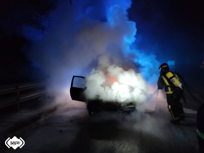 Bomberos trabajan en la extinción de un incendio declarado en un coche en Llanes.