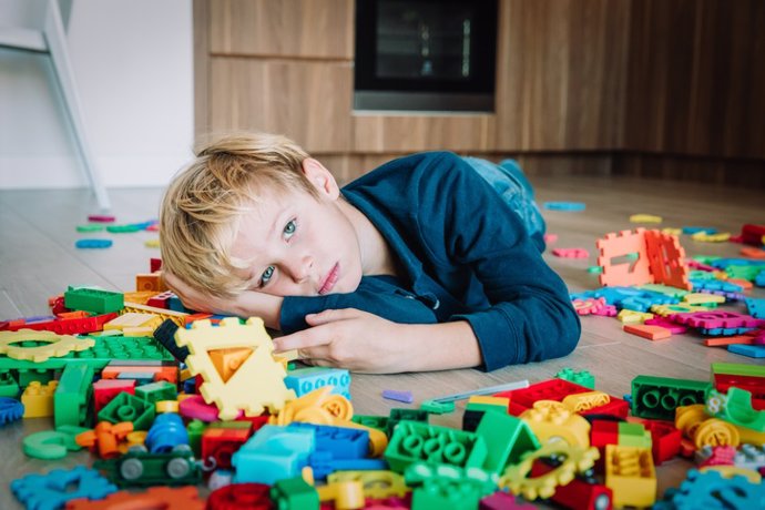 Niño triste, estrés y depresión, agotamiento con juguetes esparcidos alrededor.