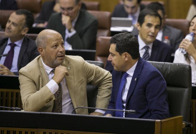 El presidente de la Junta de Andalucía, Juanma Moreno (d) conversa con  el consejero de Educación y Deporte, Javier Imbroda (i) durante el Pleno del Parlamento en una imagen de archivo