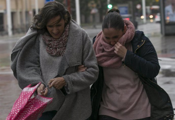 Dos personas se intentan proteger del viento en Sevilla