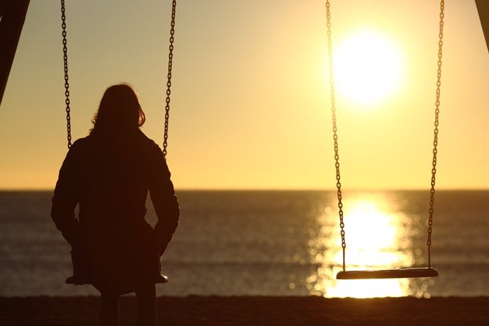 Lonely woman watching sunset alone in winter