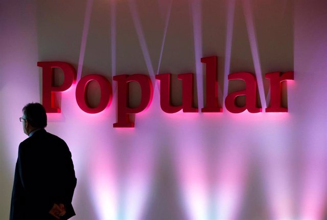 FILE PHOTO: A man stands next to the logo of Spain's Banco Popular during the bank's results presentation in Madrid