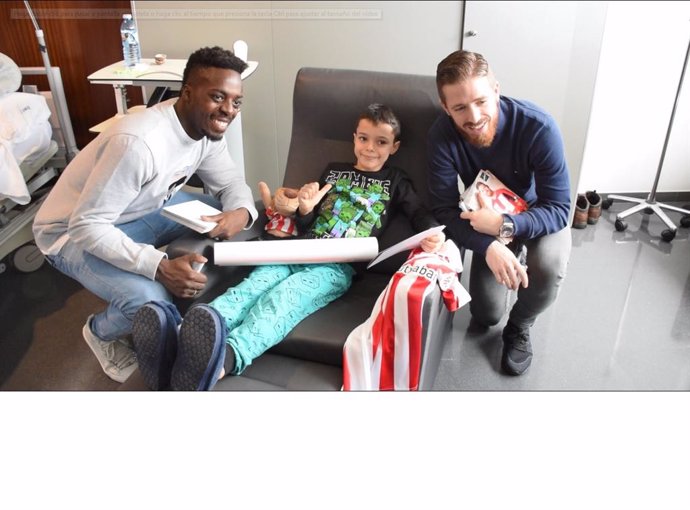 Iñaki Williams e Iker Muniain entregan una bata rojiblanca a un niño hospitalizado en Bilbao