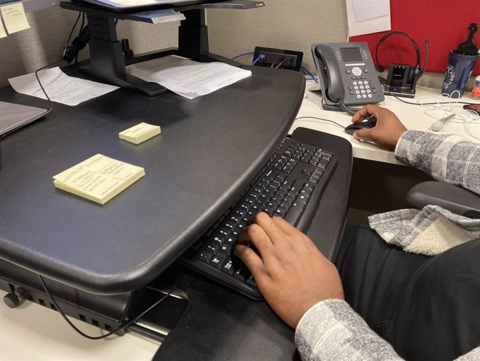 Hombre trabajando en una mesa de escritorio, oficina, ordenador, teclado