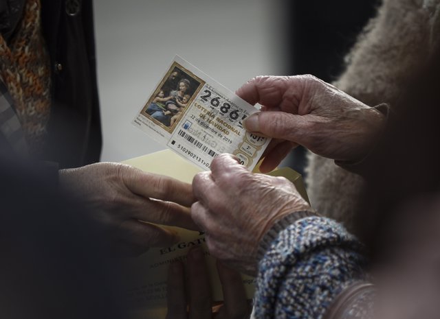 Personas guardando un décimo de lotería en un sobre. En Sevilla, a 17 de diciembre de 2019.