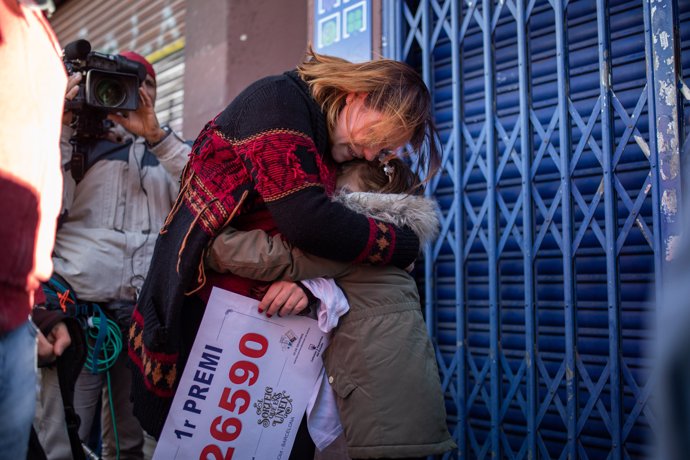 Una mujer abraza a su hija mientras sujeta el número que ha sido premiado con el Primer Premio de la Lotería de Navidad, el Gordo de la Lotería, el n 26.590, en Barcelona /Catalunya (España), a 22 de diciembre de 2019.