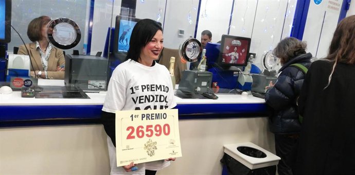 Matilde, empleada de la administración de Doña Manolita, muestra un cartel con el número agraciado con el primer premio del Sorteo Extraordinario de Lotería de Navidad.