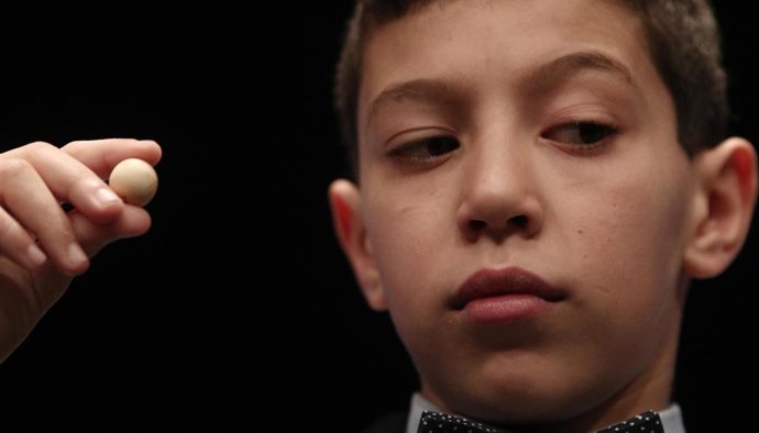 Unos de los niños de la residencia de San Ildefonso, posa con una de las bolas premiadas en el Sorteo Extraordinario de la Lotería de Navidad 2019 en el Teatro Real de Madrid (España), a 22 de diciembre de 2019.
