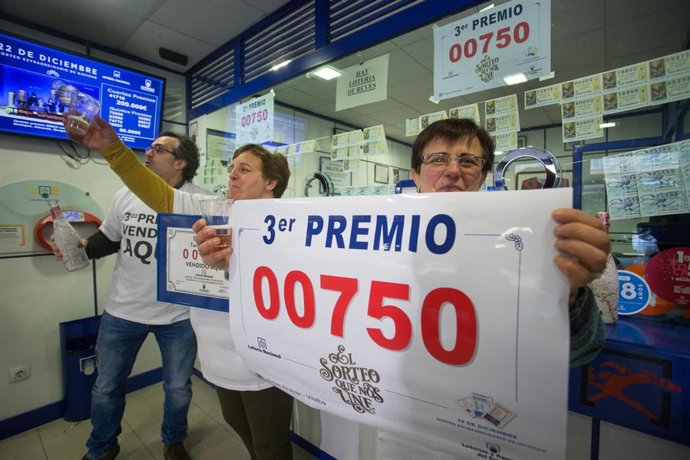 Los dueños del establecimento de lotería de Rua da Pravia, 18 de Vilalba, posan con el número 00750, premiado con el Tercer Premio del Sorteo Extraordinario de Lotería de Navidad 2019, el cual vendieron en su establecimiento, en Lugo /Galicia (España).