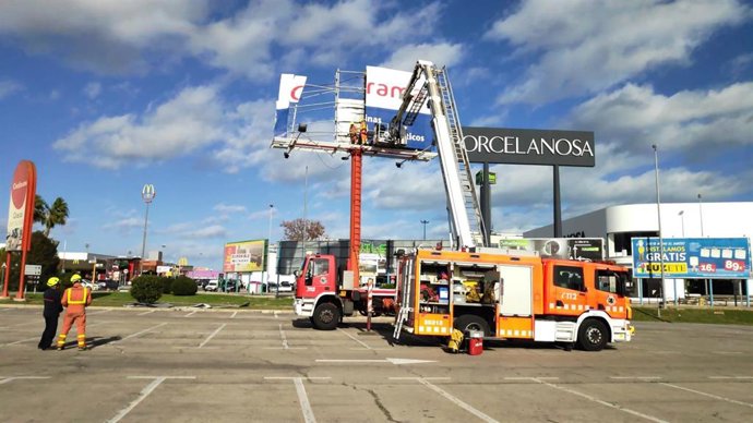 Bomberos retiran un gran cartel publicitario en un centro comercial de Alfafar (Valencia)