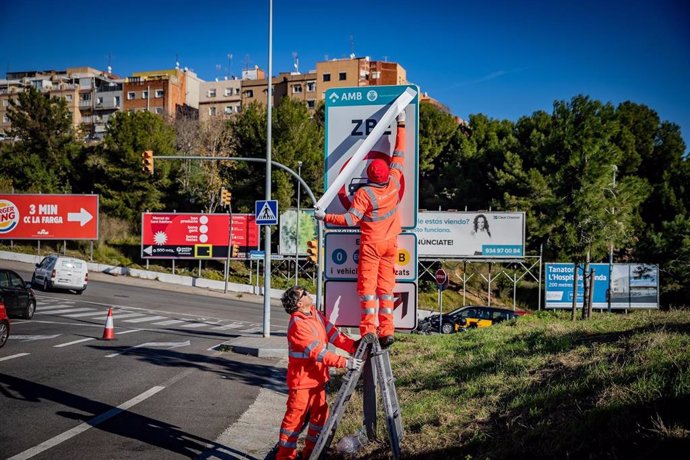 Operarios instalando las señales de tráfico definitivas de la ZBE Rondas BCN en el ramal de la salida 14 Bess de la Ronda de Dalt, en L'Hospitalet de Llobregat