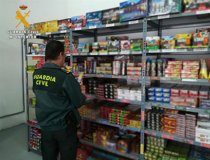 Un guardia civil revisa artículos pirotécnicos en un establecimiento que los vende.