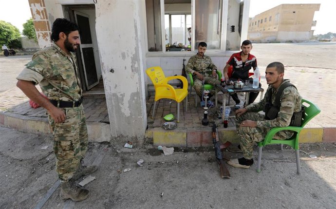 Combatientes rebeldes sirios respaldados por Turquía se sientan juntos en la ciudad fronteriza de Tal Abyad