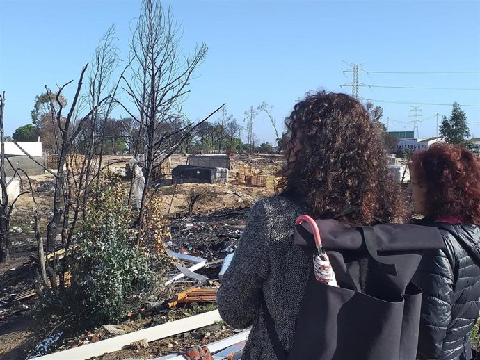Algunas vecinas miran al asentamiento chabolista calcinado en Palos de la Frontera.